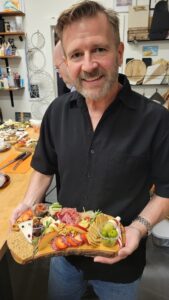 a man posing for a picture with his charcuterie board