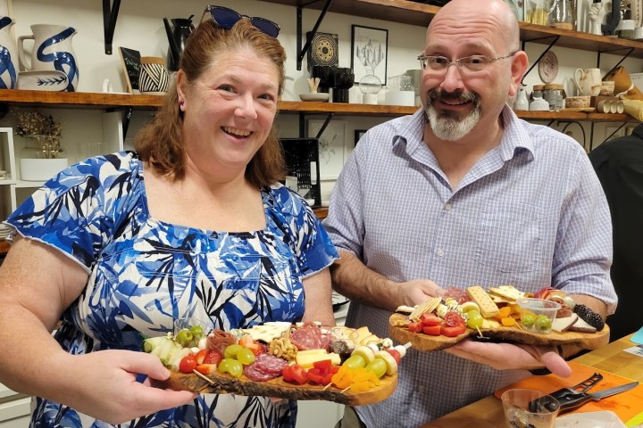 a couple posing for a picture with their charcuterie board